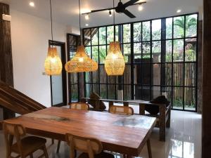 ein Esszimmer mit einem Holztisch und Kronleuchtern in der Unterkunft De, dalam secret nature in Ubud