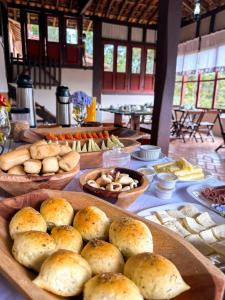 une table avec des assiettes de pain et d'autres denrées alimentaires dans l'établissement Alecrim Pousada, à Conceição da Ibitipoca