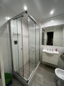 een badkamer met een glazen douche en een wastafel bij Tu departamento en Vicente López in Vicente López