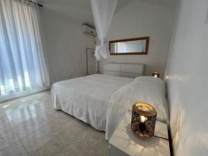a white bedroom with a white bed and a lamp at Villa Astéria in Le Diamant