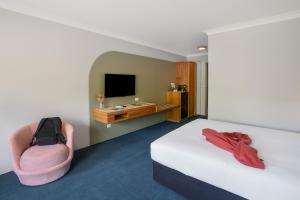 a room with a bed and a chair and a television at All Seasons Motel Armidale in Armidale +33 photos
