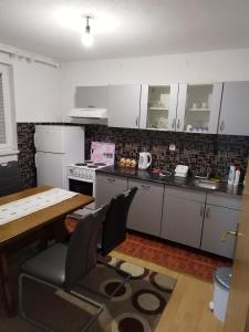 a kitchen with white cabinets and a table and chairs at Apartman Leki in Sarajevo
