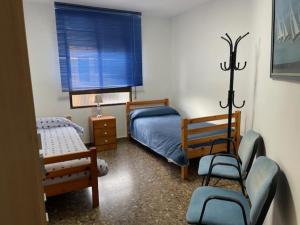 a bedroom with two beds and a chair and a window at Apartamento Diagonal in Nules