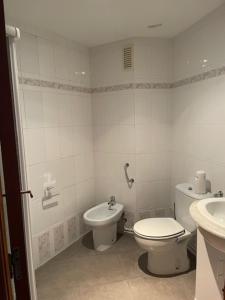 a white bathroom with a toilet and a sink at Apartamento Diagonal in Nules