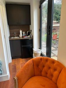 an orange couch in a room with a kitchen at Bespoke Gallery guesthouse in Hendon