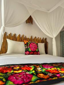 Una cama con una manta con flores. en Alito Tulum Hotel, en Tulum