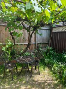 een tafel en stoelen in een tuin met een boom bij Bespoke Gallery guesthouse in Hendon