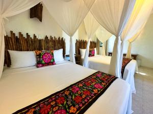 a bedroom with two beds with curtains and pillows at Alito Tulum Hotel in Tulum