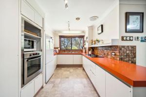 a kitchen with white cabinets and a red counter top at Rosella Retreat in Blackheath