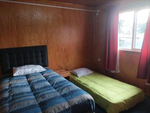 Schlafzimmer mit einem Bett und einem Fenster in der Unterkunft EL URCO CHILOE HOSTEL in Ancud