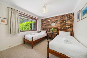 ein Schlafzimmer mit zwei Betten und einer Ziegelwand in der Unterkunft Rosella Retreat in Blackheath