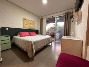 a bedroom with a bed with pink pillows on it at Pousada Recanto da Estação in São João da Boa Vista