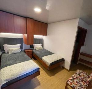 ein kleines Zimmer mit 2 Betten und einem Stuhl in der Unterkunft VILLA DE MOYA HOTEL MONGUI in Monguí