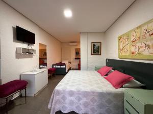 una camera da letto con un grande letto con cuscini rosa di Pousada Recanto da Estação a São João da Boa Vista