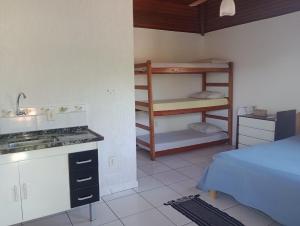 um quarto com uma cama e uma cozinha com um lavatório em Solo Buziano- Casa de Temporada em Búzios