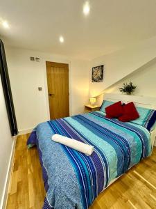 a bedroom with a large bed with blue and red pillows at Studio near Heathrow in West Drayton