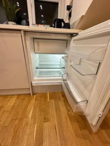 an empty refrigerator with its door open in a kitchen at Studio near Heathrow in West Drayton