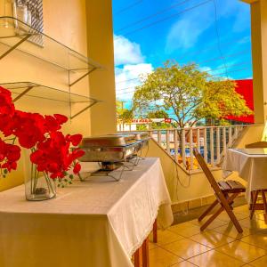 una mesa con un jarrón de flores rojas en el balcón en Pousada Casa do Ivo Santarém, en Santarém