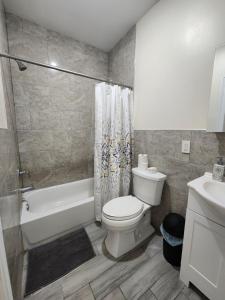 een badkamer met een toilet, een bad en een wastafel bij Pleasing 3BR Apt, Mins to NYC in Jersey City
