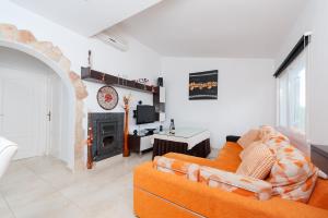 ein Wohnzimmer mit einem orangefarbenen Sofa und einem Kamin in der Unterkunft Can Rovet in Port d'Alcúdia