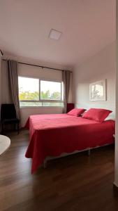 um quarto com uma cama vermelha e uma grande janela em Pousada Recanto da Estação em São João da Boa Vista