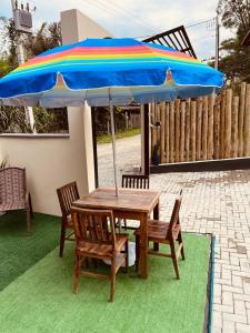 Pousada Águas da Grota في بنها: طاولة وكراسي خشبية مع مظلة