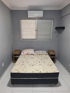 een slaapkamer met een bed en twee nachtkastjes bij Cobertura Guarujá in Guarujá