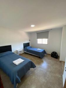 Un dormitorio con una cama azul y una ventana en Departamentos Los Cardos en San Rafael