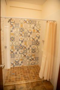 a bathroom with a shower with a tiled wall at Estancia 105 in La Paz