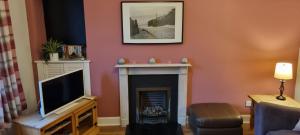 uma sala de estar com lareira e televisão em Millhill St Dunfermline em Dunfermline