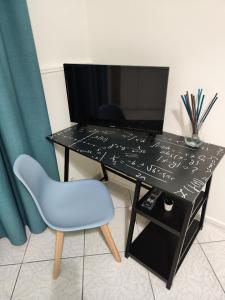 a black desk with a blue chair and a television at Nalusa Home in Sarno