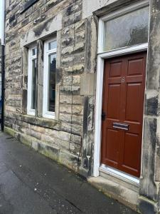 een rode deur aan de zijkant van een bakstenen gebouw bij Millhill St Dunfermline in Dunfermline