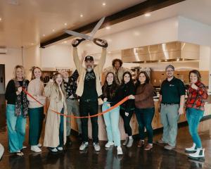 a group of people are cutting a ribbon at Summit Lofts Boutique Hotel in Mount Shasta