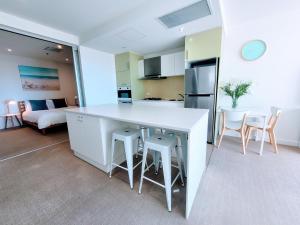 a kitchen and living room with a white counter and chairs at CityViews @ Glenelg * Pool/Beach * Free Parking * in Glenelg