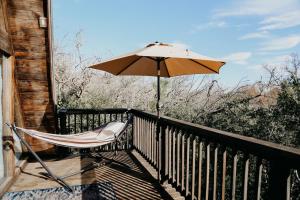 a chair and an umbrella on a balcony at The Maverick: A-Frame w/ Hammock and Tree Top View in New Braunfels