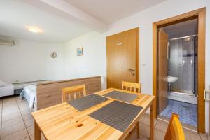 Un comedor con mesa de madera y un dormitorio. en Apartments Obradović, en Dramalj