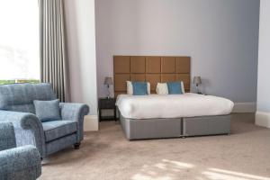 a bedroom with a bed and a couch and a chair at Oatlands Park Hotel in Weybridge