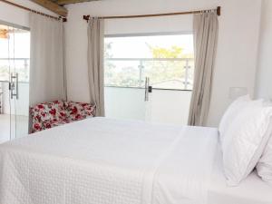 a bedroom with a white bed and a window at Residencial Santa Fe in Trancoso