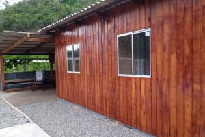 een houten gebouw met 2 ramen en een patio bij Chácara em Luis Alves in Luís Alves