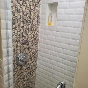 a bathroom with a shower with a tiled shower at STUDIO and ONE BEDROOM APARTMENTS in Bronx