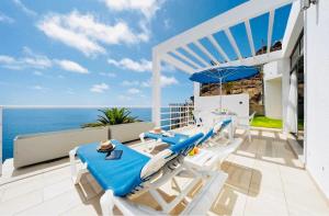 波多黎各的住宿－Bahia & Ocean Views - Holiday Club Deluxe Private Suite，一个带椅子和遮阳伞的庭院和大海