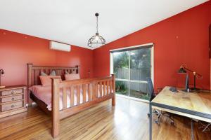 Schlafzimmer mit roten Wänden, einem Bett und einem Schreibtisch in der Unterkunft Florida Bliss in Smiths Beach