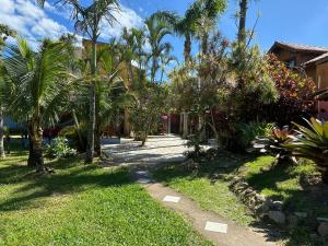 a path through a yard with palm trees and a house at CHALÉ 50 METROS DA PRAIA- CHALÉS SOLANA in Garopaba