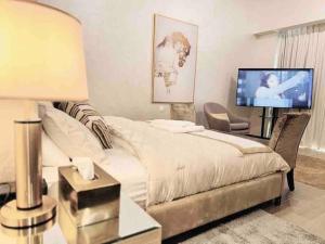 a bedroom with a bed and a flat screen tv at Mayan Studio Apartment in Abu Dhabi