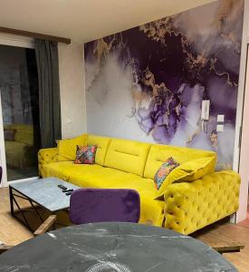 a yellow couch in a living room with a table at Apartman Monti Vlašić in Vlasic