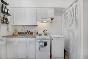 cocina blanca con fogones y fregadero en Historic Petworth Homestay, en Washington