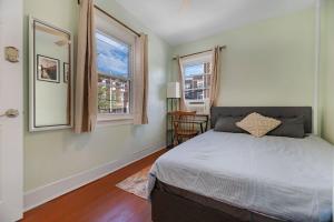 a bedroom with a bed and two windows at Historic Petworth Homestay in Washington
