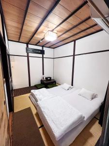 um quarto com uma cama branca num quarto em Bighem Maison em Izumi-Sano