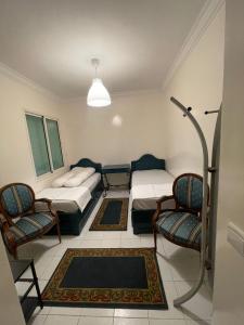 a room with two beds and two chairs at Charmant Appartement Meublé en face de la Mosquée Hassan II : Emplacement Idéal au Cœur de Casablanca in Casablanca