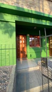 a green building with a door and two windows at Ruca Epu in Las Grutas